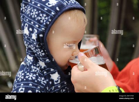 A small kid drinking beer (alcohol) from a glass in hand of adult Stock Photo - Alamy