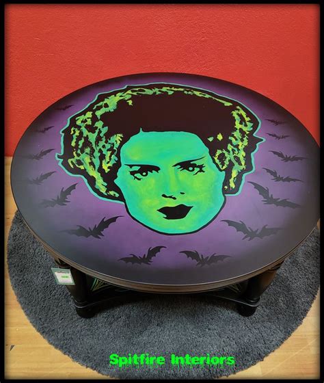 a table with a painting of a woman's face and bats on the top