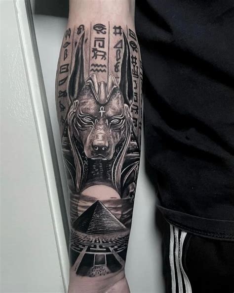 a man's arm with an egyptian mask and pyramids on the other side