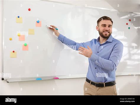 Portrait of young teacher writing on whiteboard in classroom Stock Photo - Alamy