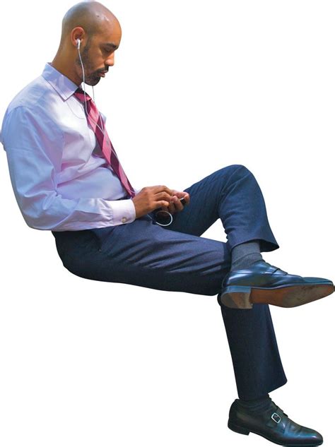 a man sitting on top of a chair with his legs crossed and headphones in ...