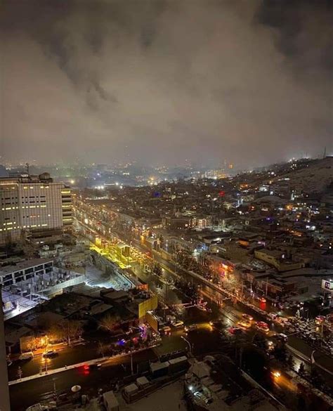 an aerial view of a city at night with buildings and lights in the distance,