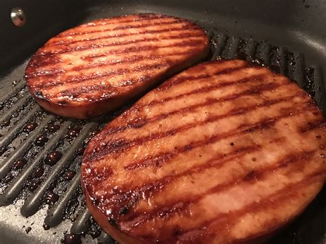 two hamburger patties cooking in a frying pan