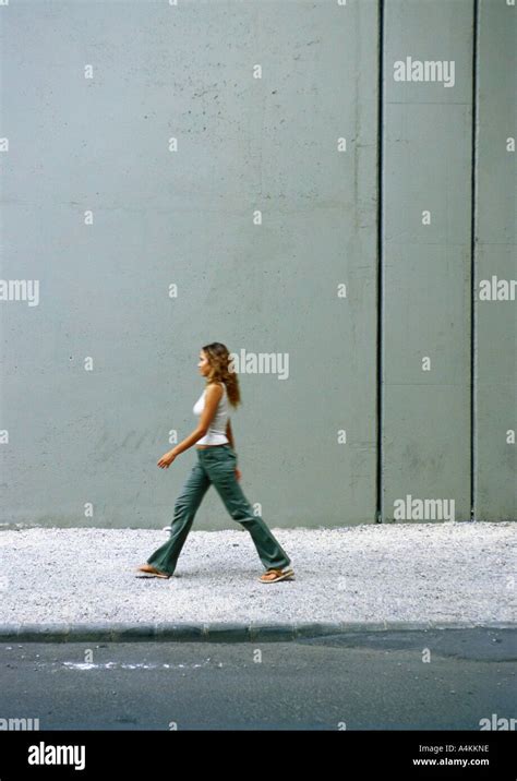 Woman walking on sidewalk, side view Stock Photo - Alamy