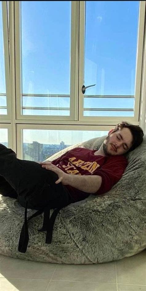 a man laying on top of a bean bag chair in front of a large window