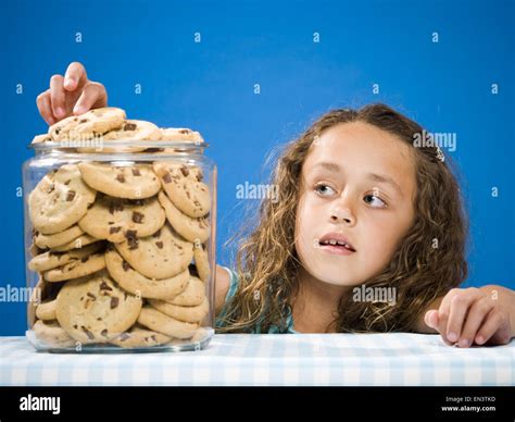 Girl taking chocolate chip cookie from jar Stock Photo - Alamy