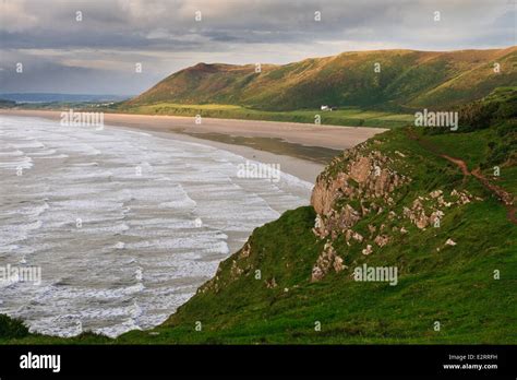 Overlooking Rhossili bay. Surf racing in, lit by the evening sun Stock ...