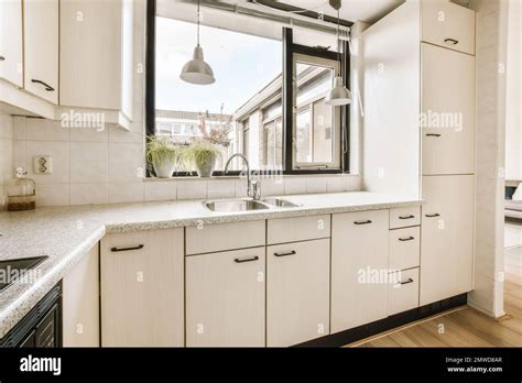 a kitchen area with white cabinets and black trim around the window ...