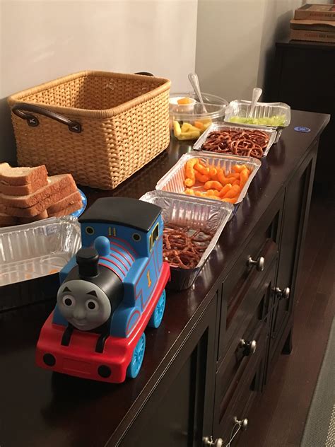 a toy train sitting on top of a wooden table next to containers filled with food