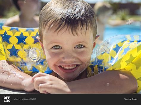 Boy wearing arm floaties in a swimming pool stock photo - OFFSET