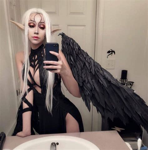 a woman is taking a selfie in front of a mirror with an angel wings