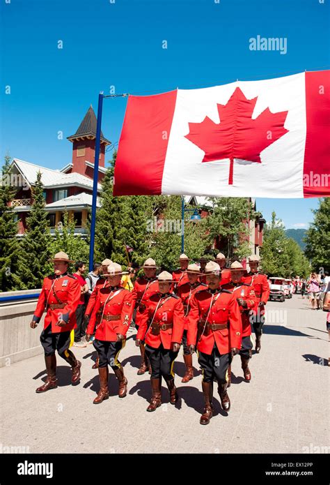 Royal Canadian Mounted Police officers parade under a Canadian flag in ceremonial red serge ...