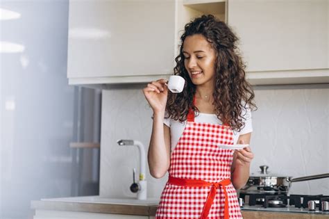 Free Photo | Young woman drinking coffee at the kitchen in the morning