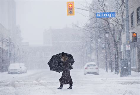 A woman walks in downtown in St. Catharines, Ont., as a winter storm ...