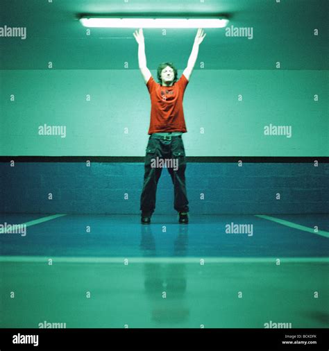 Young man reaching toward fluorescent light Stock Photo - Alamy