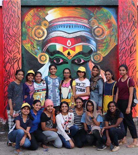 a group of people standing in front of a painting on the side of a building