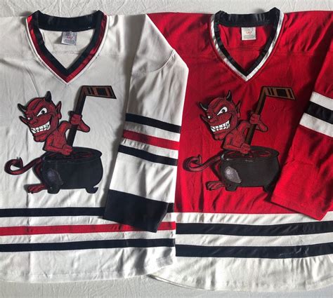 two hockey jerseys with cartoon characters on them, one is red and the ...