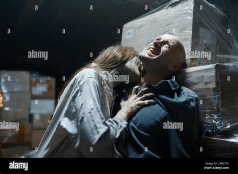 Female zombie bites a man in the neck, death trap Stock Photo - Alamy