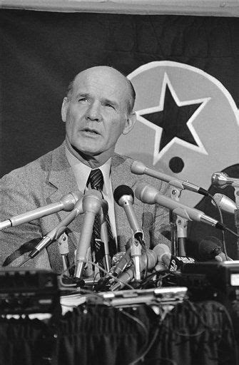 black and white photograph of man in front of microphones