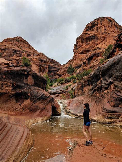 a man standing in the middle of a river surrounded by red rocks and ...