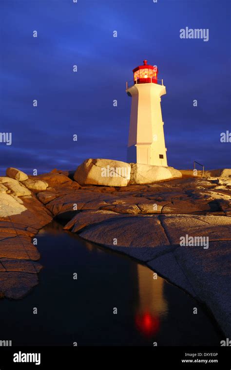 A light-painting and reflection of Peggy's Cove lighthouse on a stormy ...