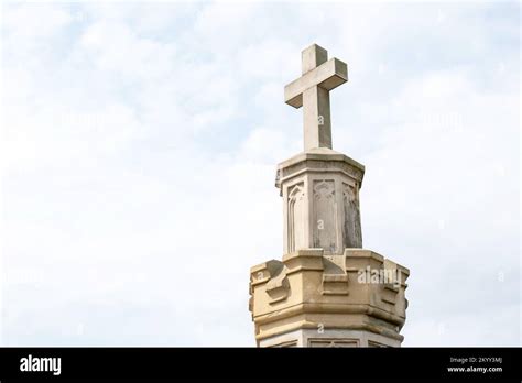 Old stone cross and light blue sky simple abstract background, copy space. Old cemetery obelisk ...