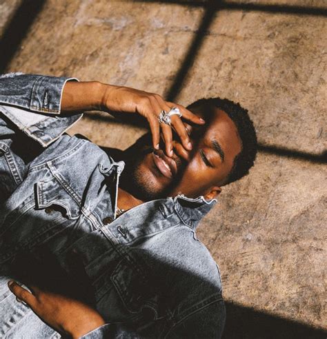 a man laying on the ground with his hands in his face and wearing a denim jacket