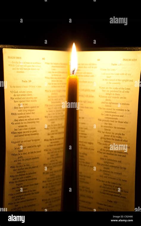 An open bible with illuminated candle in between Stock Photo - Alamy