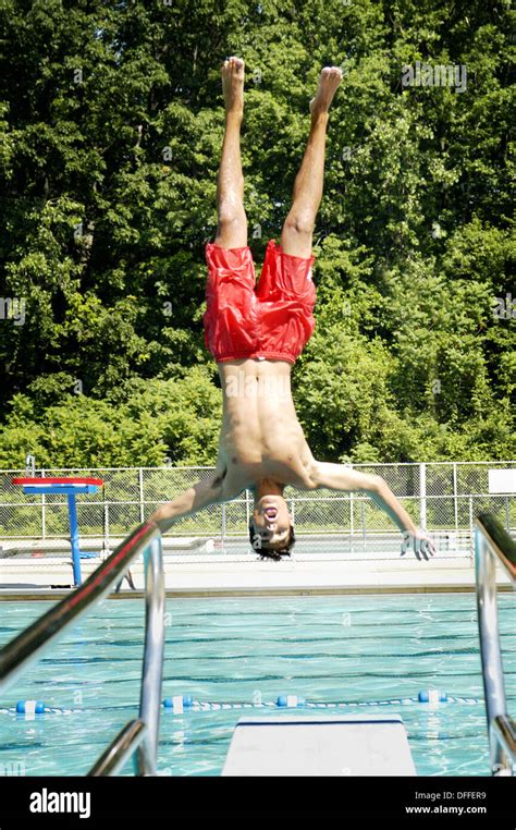 Teen shows of diving and jumping skills from diving board into pool ...