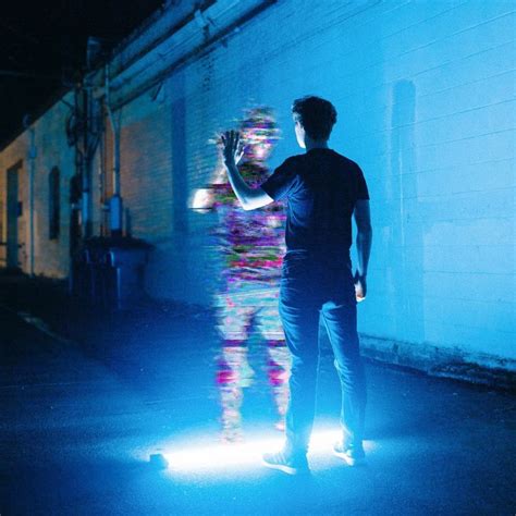 a man standing in front of a wall with his hand up to the light shining ...