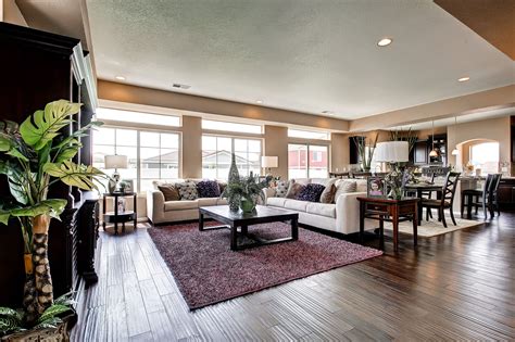 a living room filled with furniture and lots of windows next to a wooden floor covered in plants