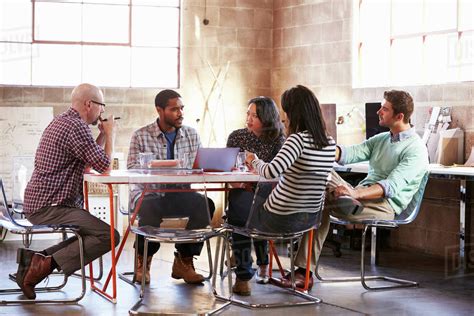 Group of designers having meeting around table in office - Stock Photo - Dissolve