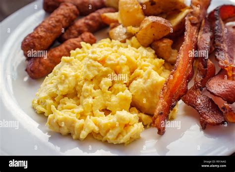 Scrambled eggs with breakfast sausage home fries and bacon Stock Photo ...