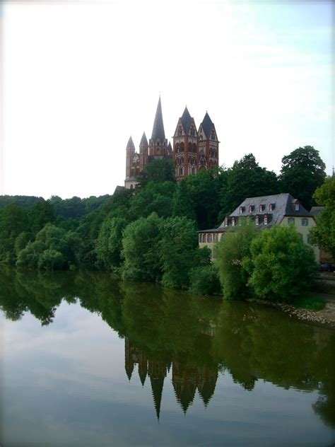 a large castle sitting on top of a lush green hillside next to a river ...