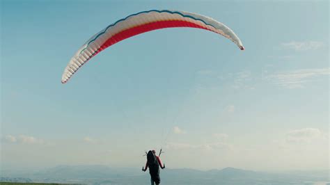 Professional paraglider with parachute run and take off from mountain top. Launch into air on a ...