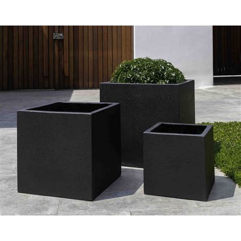 three black square planters sitting on the ground