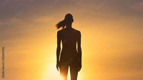 Silhouette of woman's standing in the sunset sky. Stock Photo | Adobe Stock