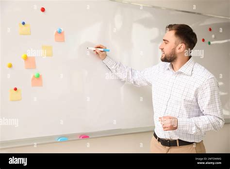 Portrait of young teacher writing on whiteboard in classroom Stock Photo - Alamy