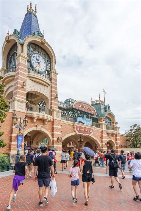 many people are walking around in front of a building with a clock on ...