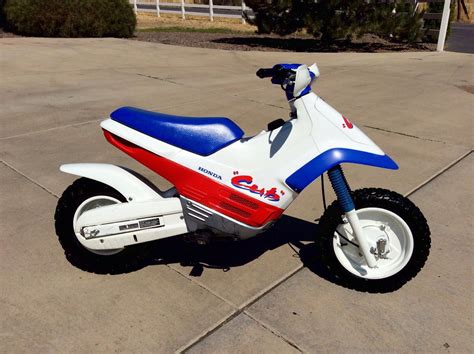 a red, white and blue dirt bike parked on concrete