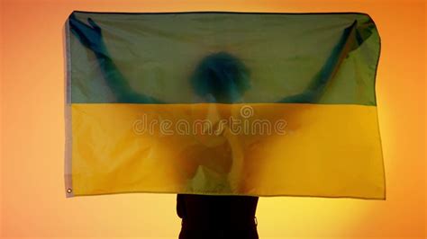 Person Silhouette Holding Big Flag Against Yellow Background. Silhouette of Man with National ...