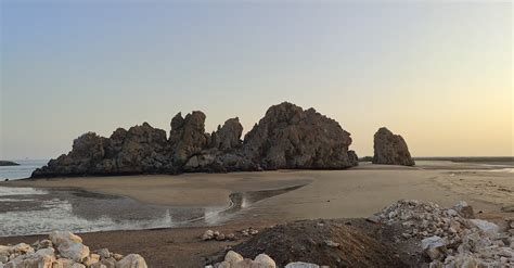 A beach with rocks and sand at sunset · Free Stock Photo