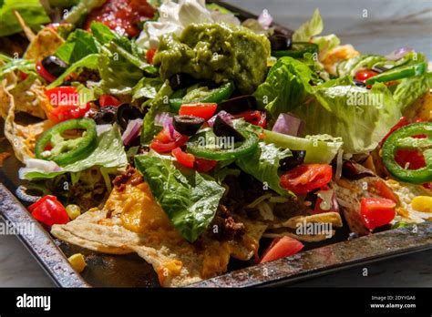 Loaded toppings beef nachos with guacamole sour cream and tomato salsa Stock Photo - Alamy