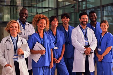 Portrait Of Smiling Medical Team Standing In Modern Hospital Building ...