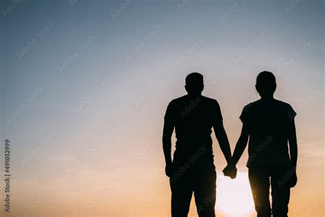 Silhouette couples are holding hands in a time of warm light. Stock Photo | Adobe Stock