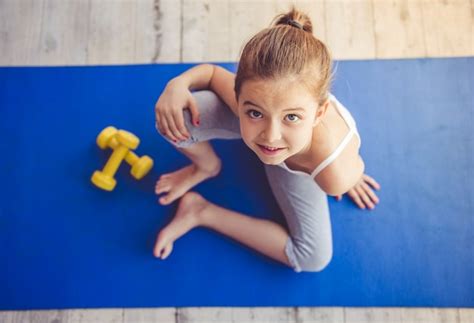 Premium Photo | Charming little girl is sitting on yoga mat