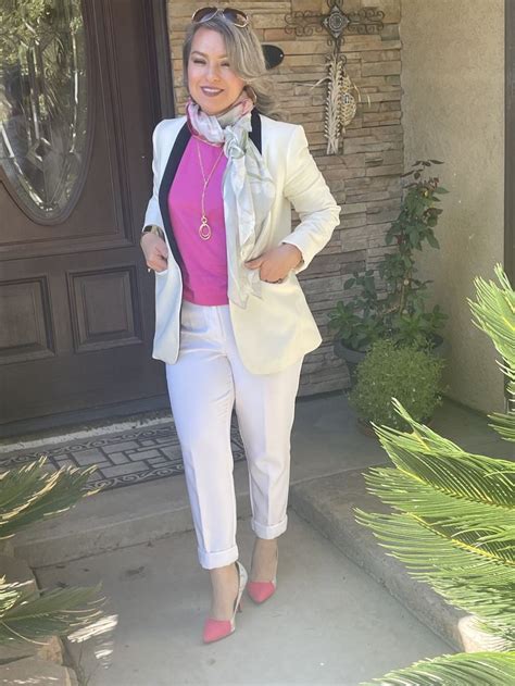 a woman standing in front of a door wearing white pants and a pink ...