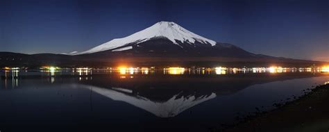 a night view of a snow covered mountain with lights reflecting in the water