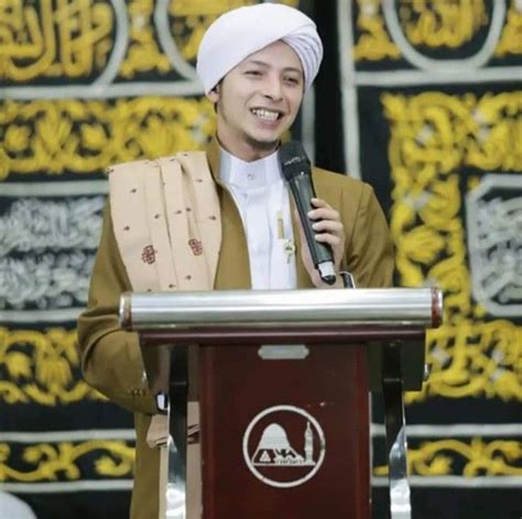 a man standing at a podium with a microphone in his hand and wearing a turban