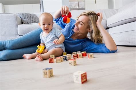 Madre que mira al bebé jugando con juguetes en la sala de estar ...